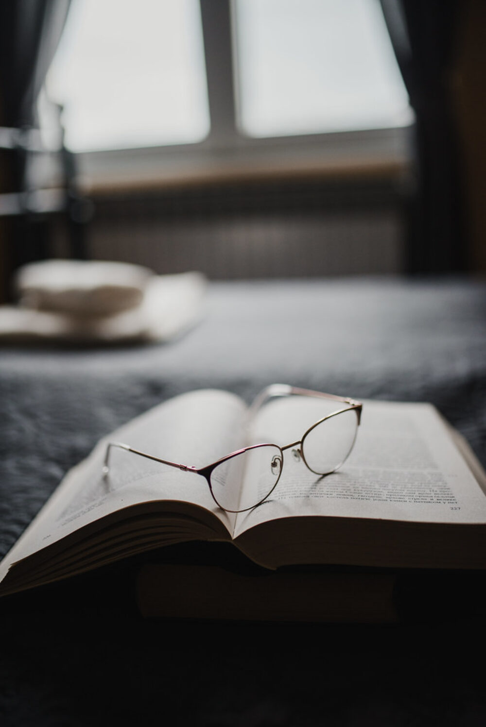 A pair of reading glasses resting on an open book.