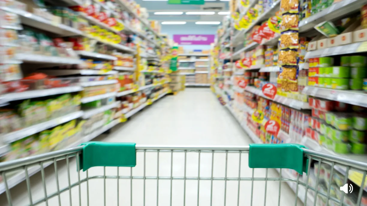 Corsia di un supermercato vista da dietro un carrello della spesa.
