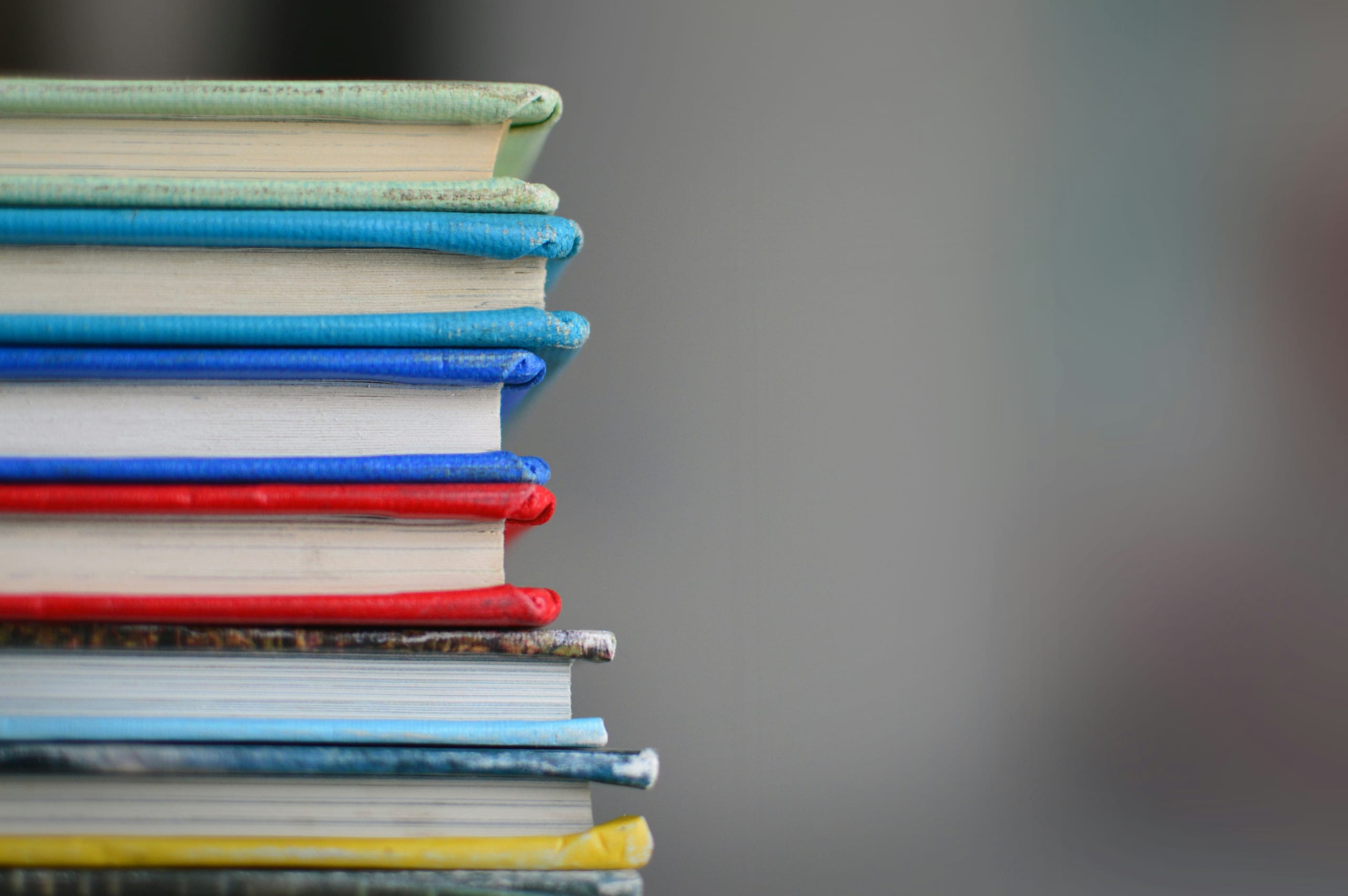 Colorful stacked book spines in various shades, showcasing a vibrant collection of literature.