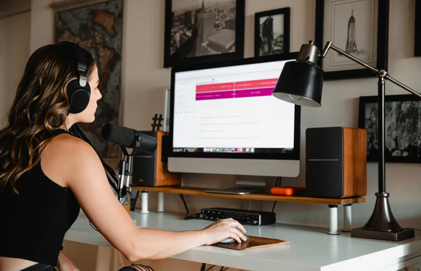Woman with a headset working on a white desk on a computer