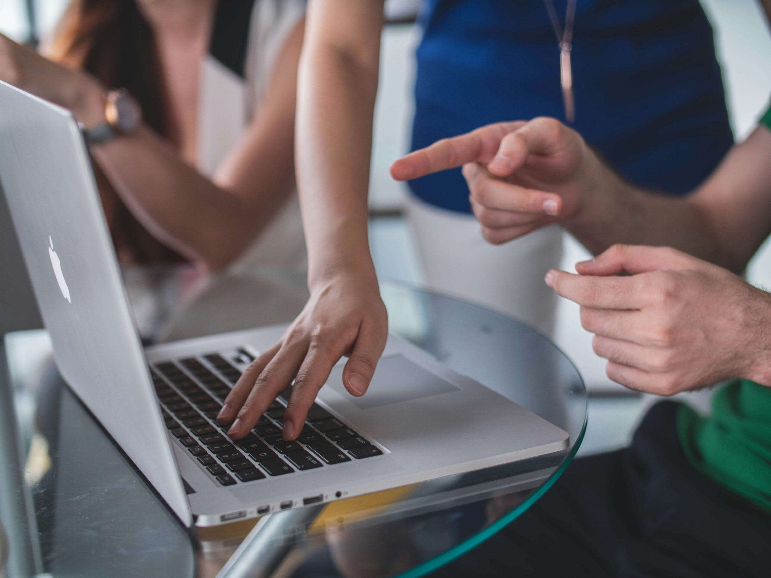People pointing at a laptop screen.