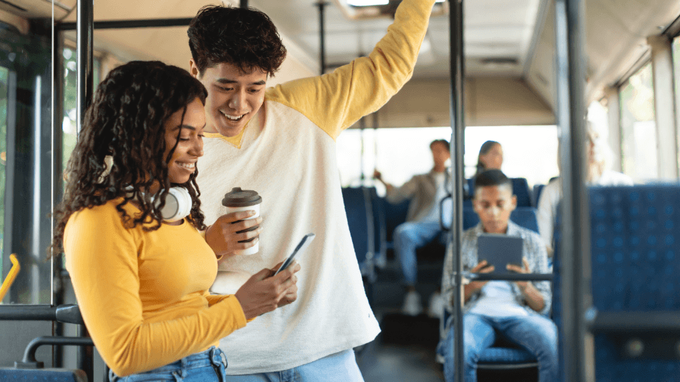 Dos personas mirando un smartphone en un autobús.