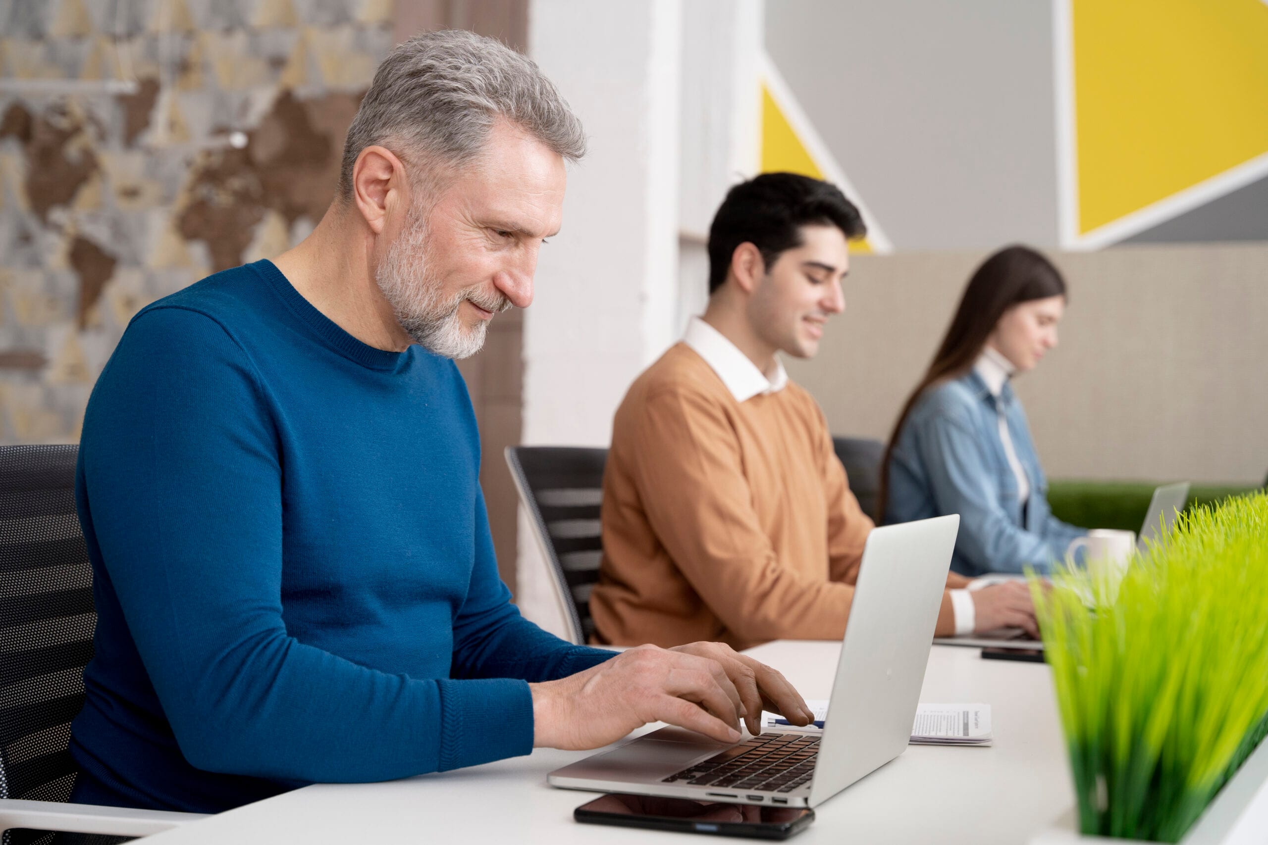 Three people are in front of their laptops.