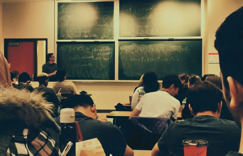 Students sitting on chairs in front of chalkboard - Bridging the accommodations gap in K12 and higher education
