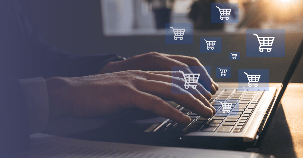 A person is typing on their laptop with shopping cart icons floating above the keyboard.