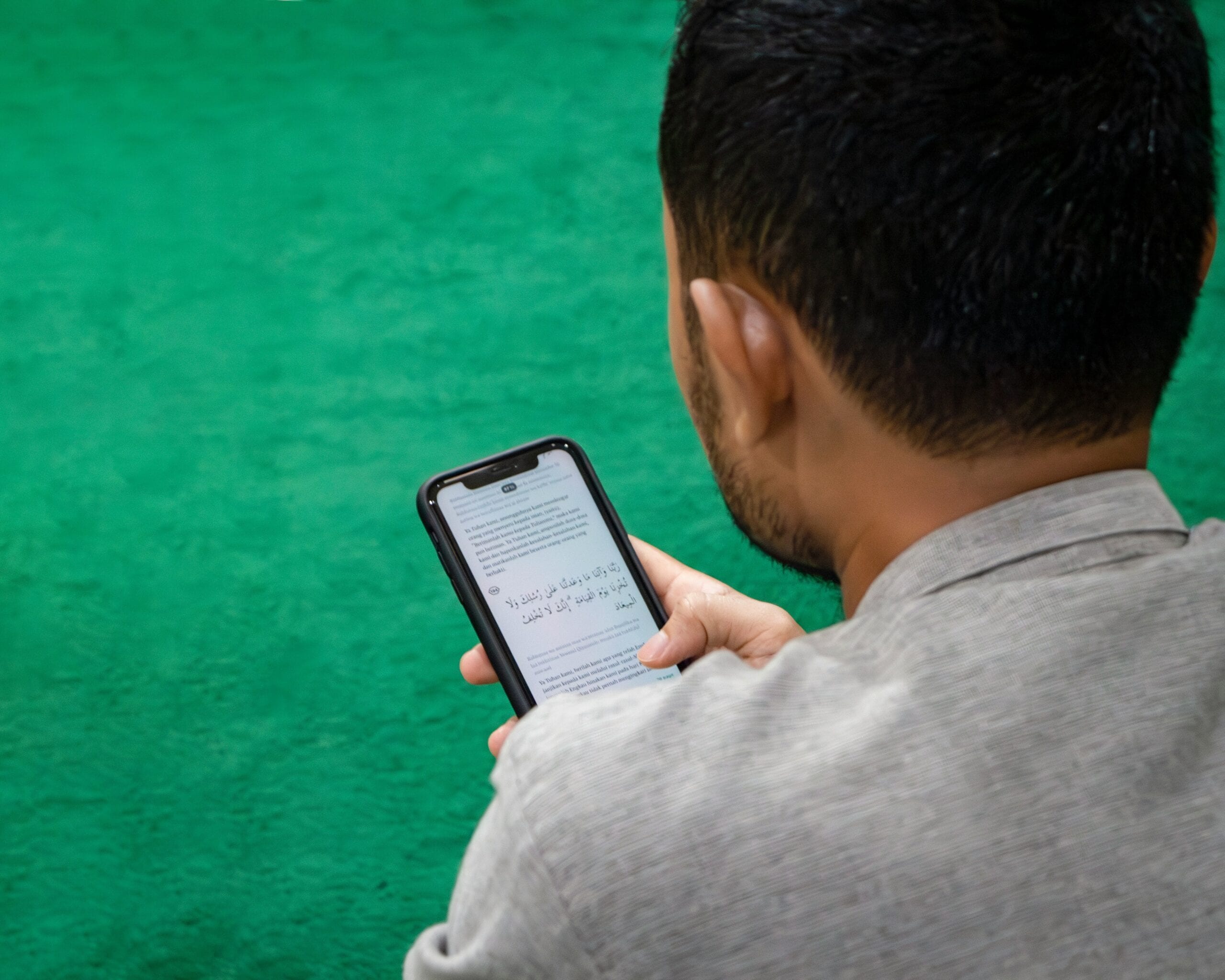 A man reading an arabic text message on his phone.