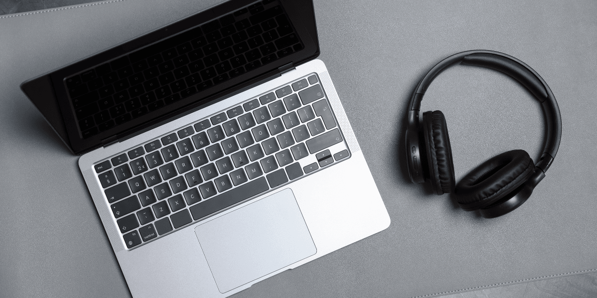 Une photo d’un ordinateur portable argenté et d’un casque noir sur un bureau gris.