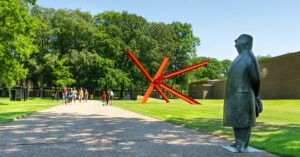 A statue in the foreground and a garden behind.