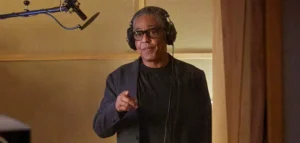 Giancarlo Esposito wearing headphones and standing in a recording studio.