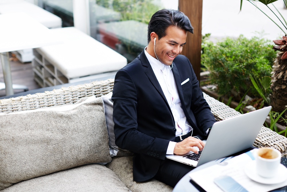 Businessman listening to content on his laptop with ear buds