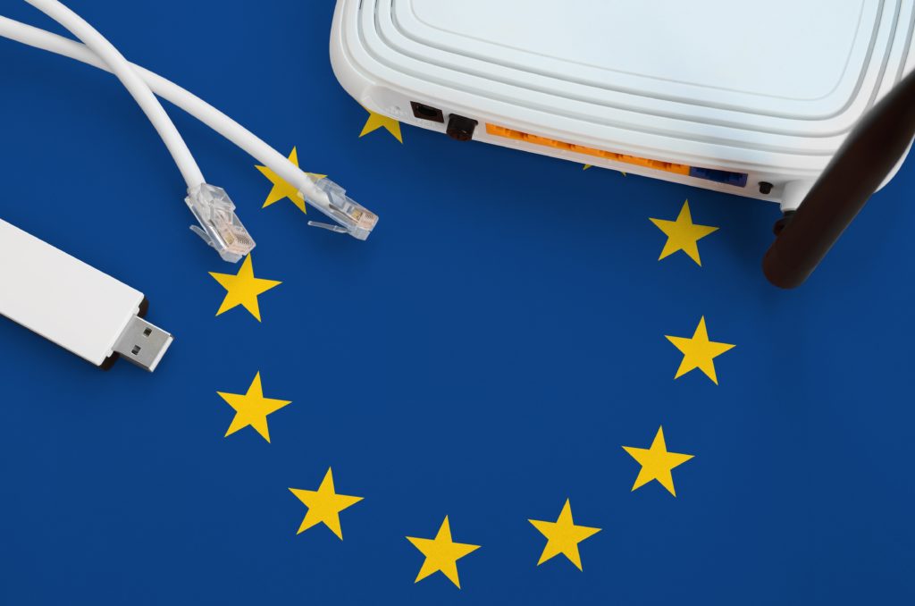 European union flag depicted on table with internet cable, wireless usb wi-fi adapter and router.