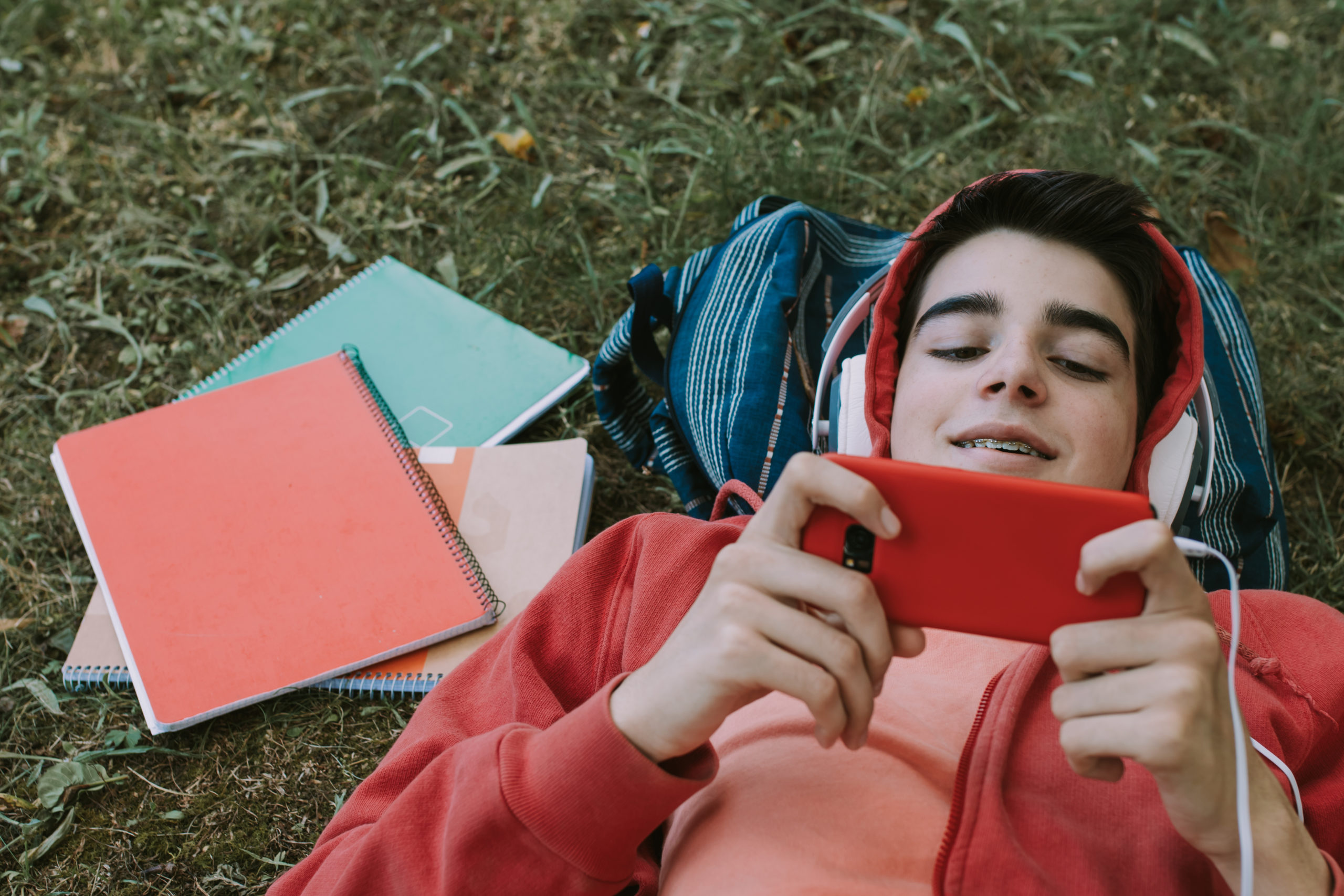 Élève allongé sur l'herbe écoutant un e-book.