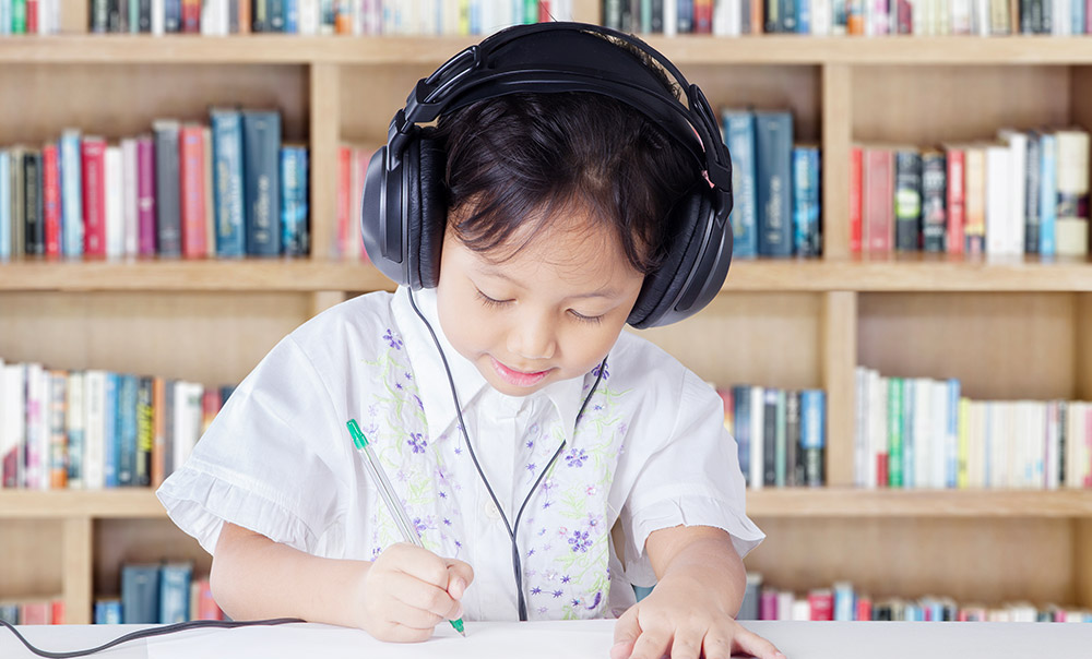 Young boy with headphones in a school library